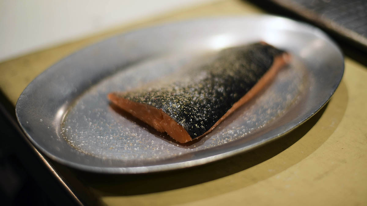 Chef Matthew Dolan salts and peppers a fresh piece of salmon 