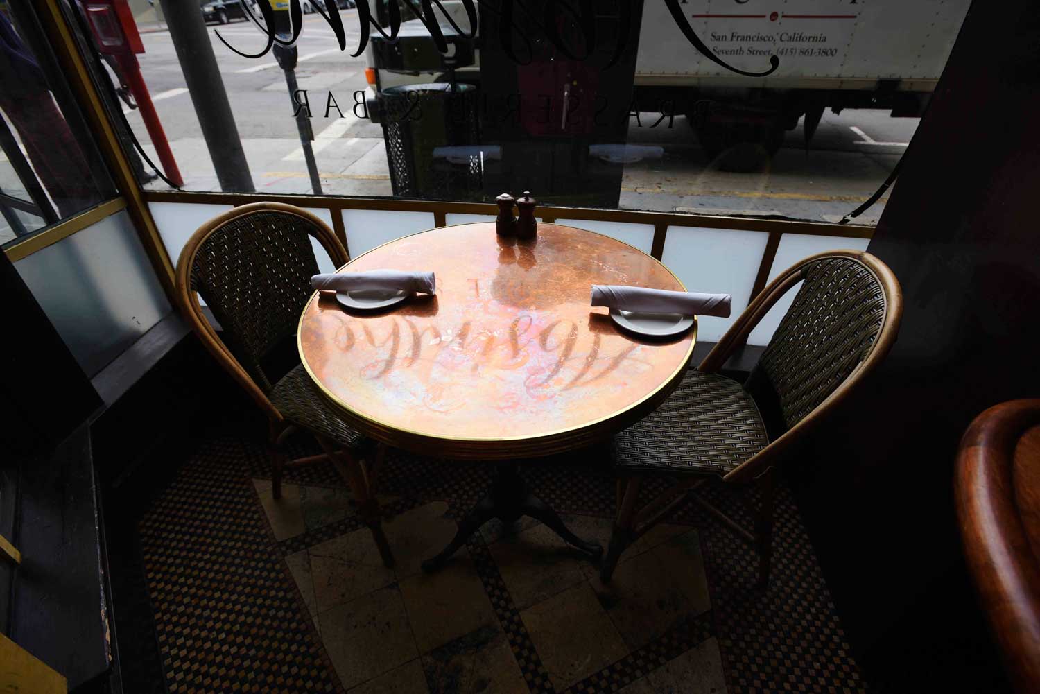 The Absinthe logo reflects in the marbly bistro seats at the front windows