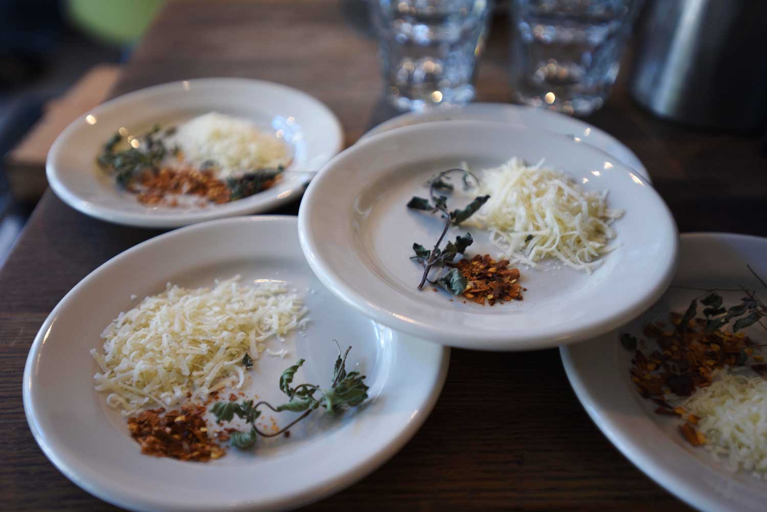 Parmesan, dried basil, and dried hot pepper garnishes wait to be served with pizzas at Pizzeria Delfina