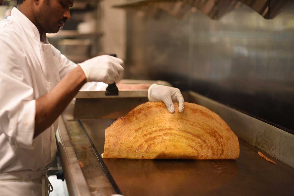 The dosa is prepared much like a French crepe, using circular motions on the griddle. Once the dosa is fried, the chef folds the dosa over any filling. 