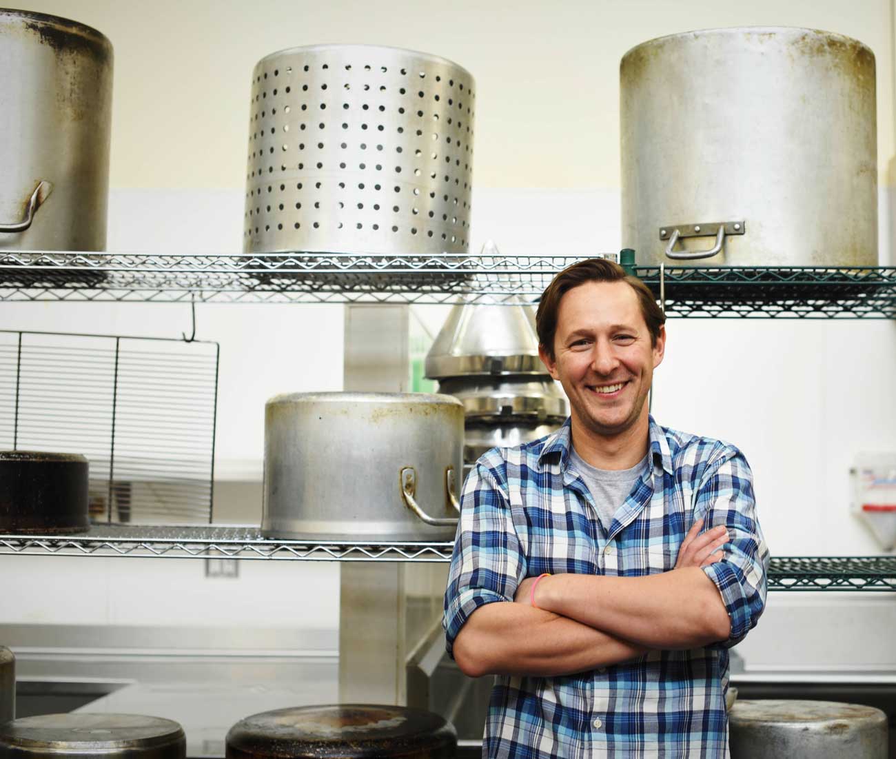 Caleb Zigas, Executive Director of La Cocina, smiles in the sunny commercial kitchen
