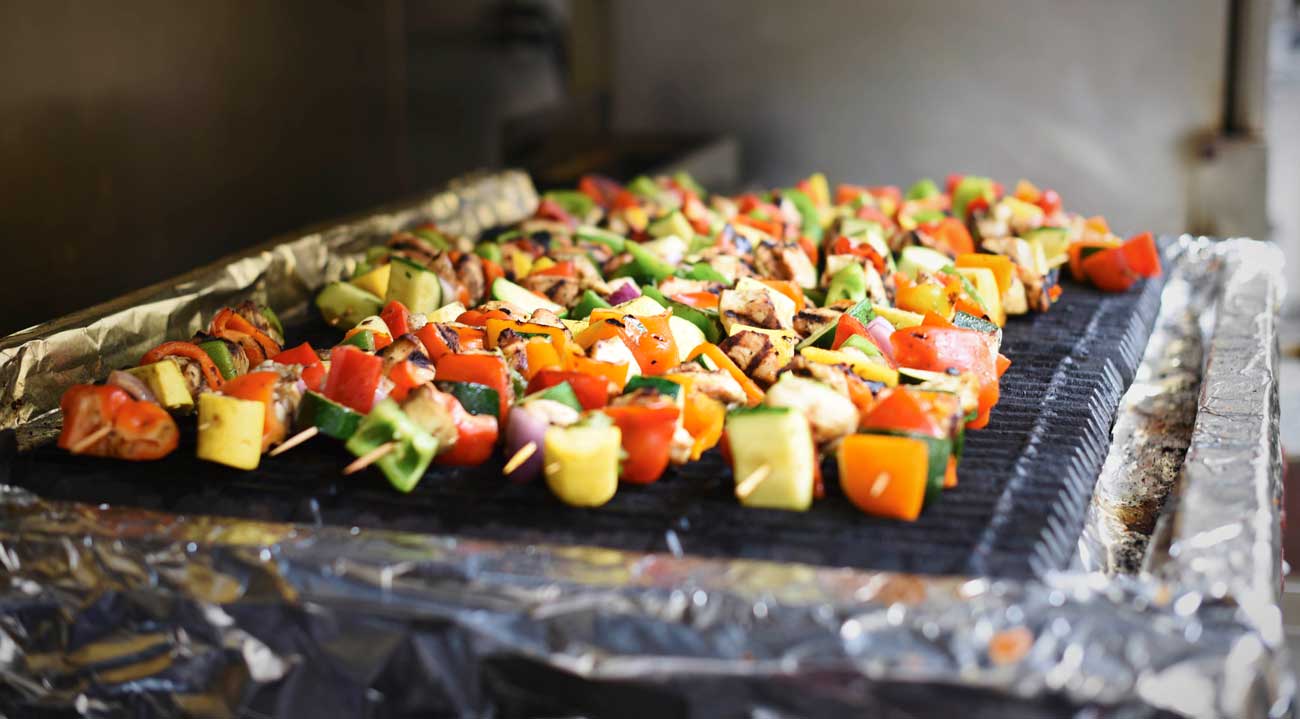 Rows of colorful kebabs cook on the stove