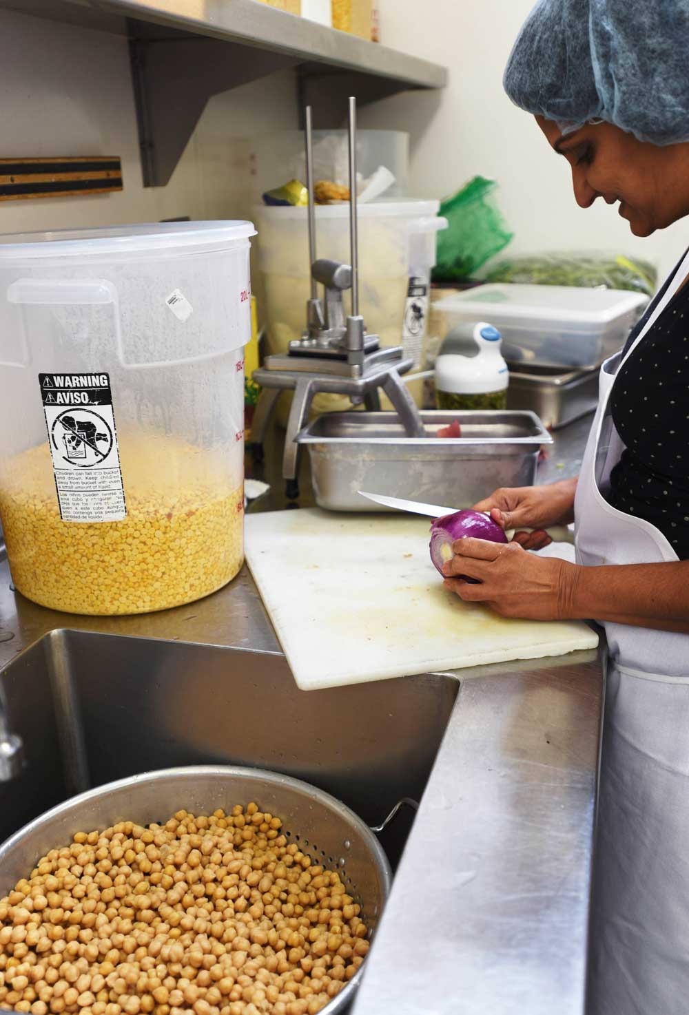 Slicing a red onion that will be mixed with garbonzo beans