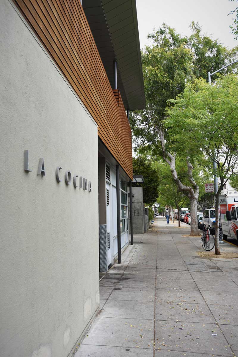 A La Cocina employee strolls down Folsom Street and stretches after a long day of prepping with the incubator participants in the kitchen