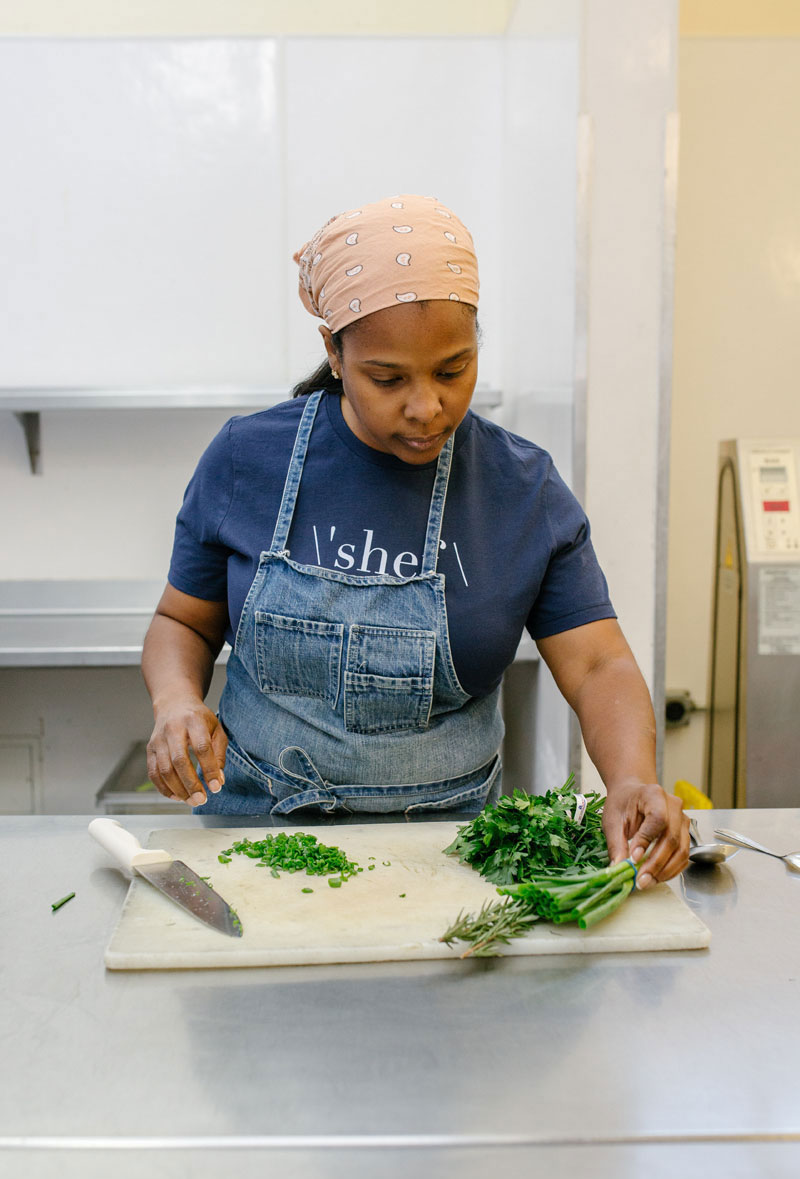 Chef Fernay McPherson of Minnie Bell's preps herbs on a cutting board 