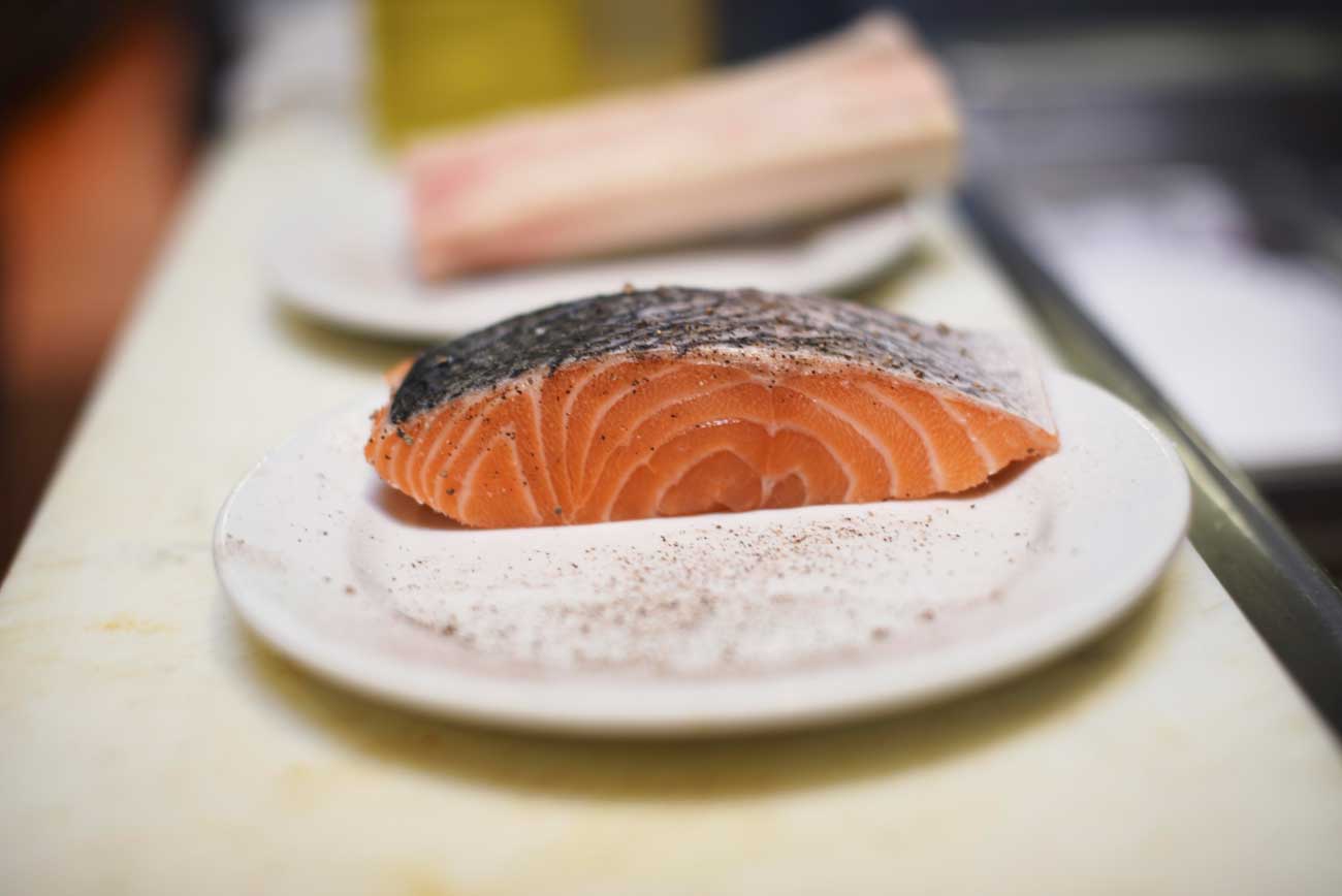 A juicy, fresh cut of salmon is peppered before being pan-fried. 