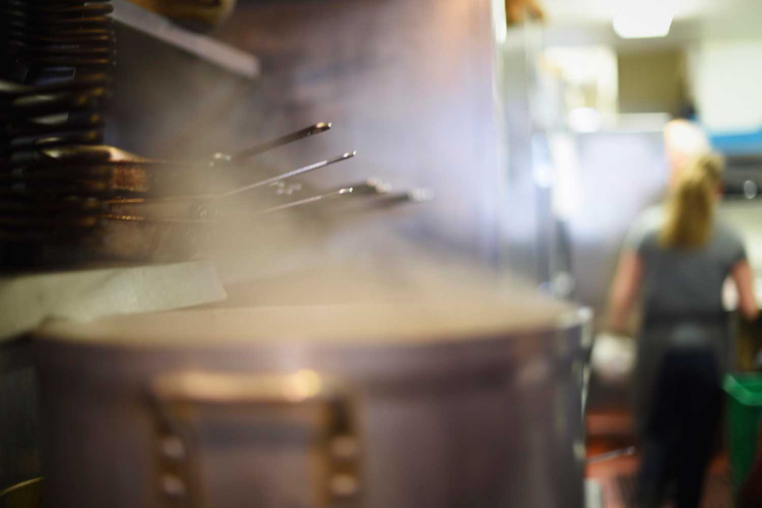 Chef Trish Tracey is seen through the steam of the broth that simmers all day in Myriad's kitchen. 