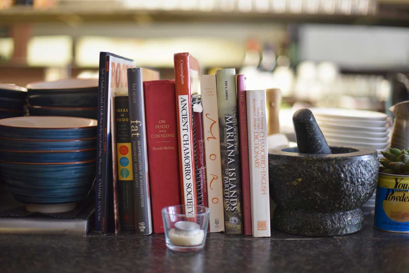 Books about the history of Guam and the cooking of the ancient Chamorro people line the kitchen counter at Prubechu. 