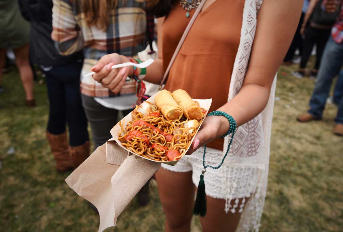 Showing off her order: fried noodles and egg rolls, topped with Sriracha.