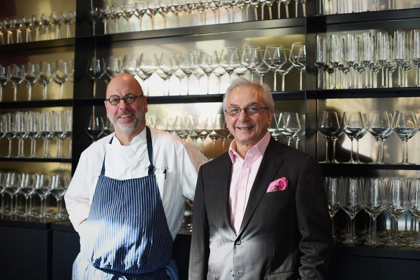 Chef Staffan Terje and Umberto Gibin stand by the wall of wine glasses at Volta.