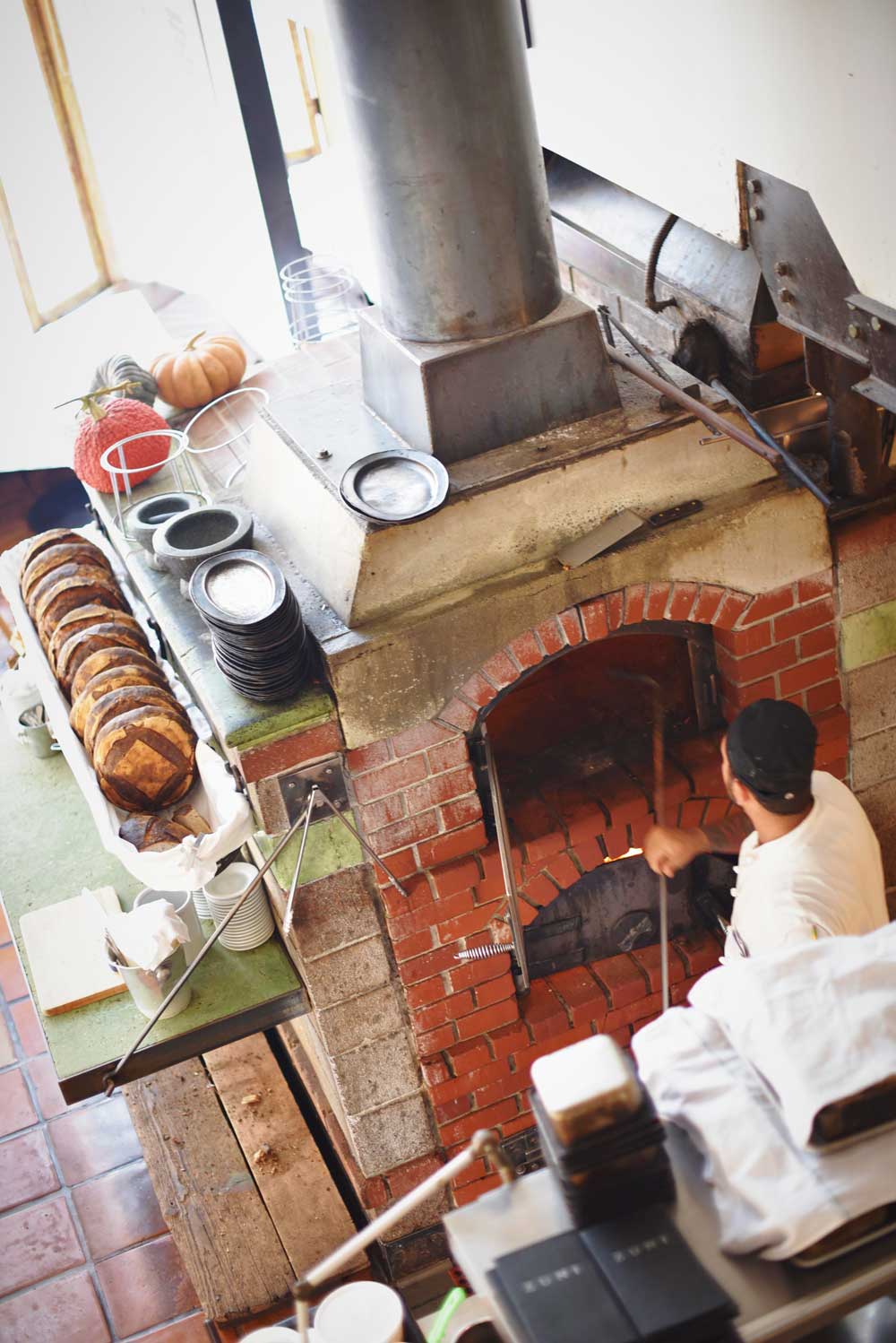 A chef cleans out the wood burning oven.