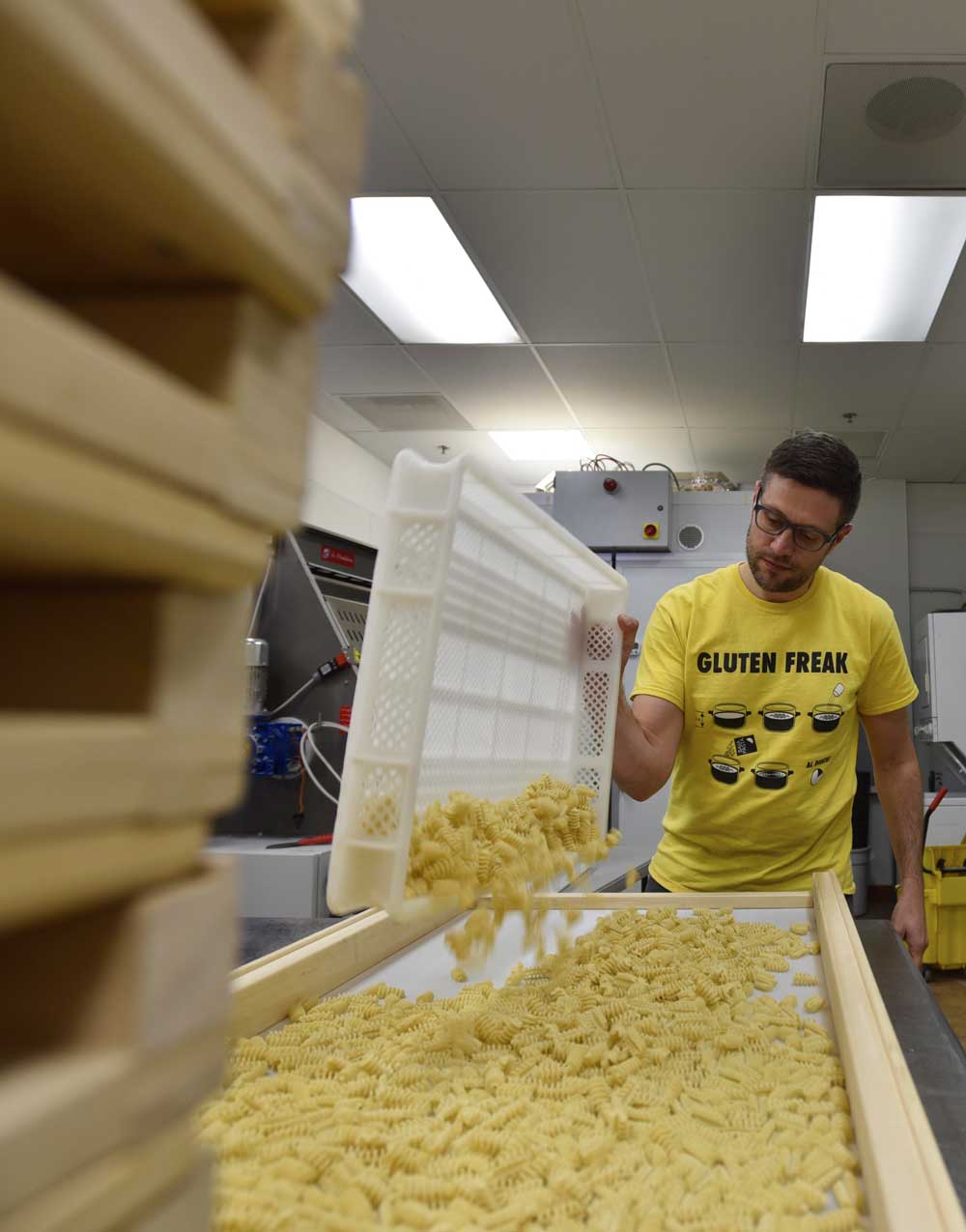 Dario moves freshly formed pasta to the drying tray.