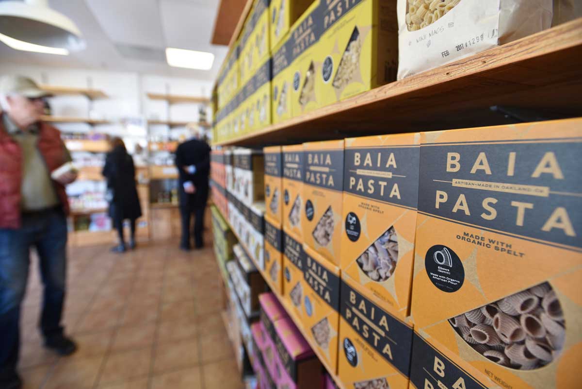 Customers select pasta packaged in brightly colored boxes in Oakland's Baia Pasta shop.