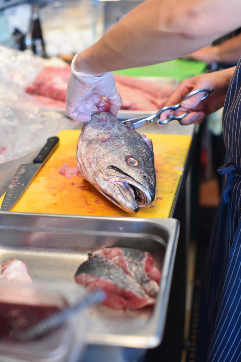 Chef Kris Toliao cleans and prepares a whole fish, starting with the head  