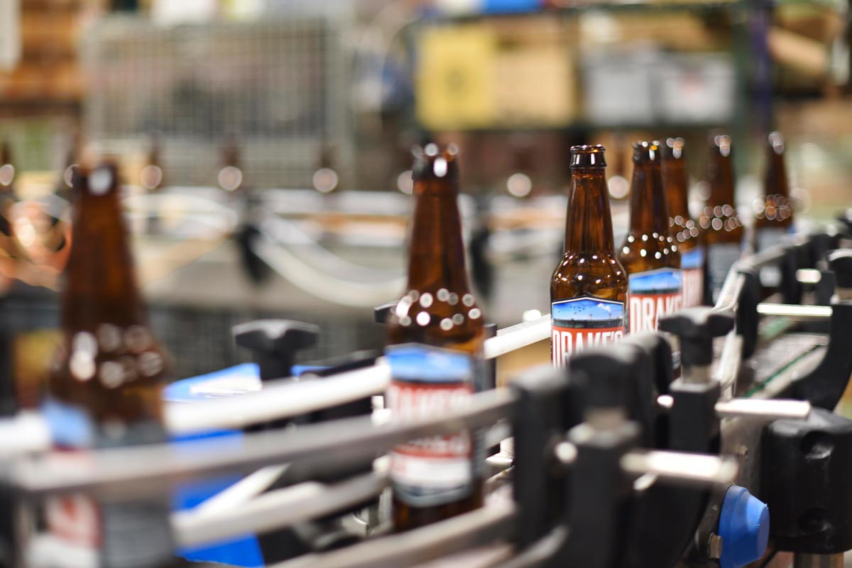 Freshly labeled, Drake's IPA bottles prepare to get cleaned and filled with freshly brewed beer  
