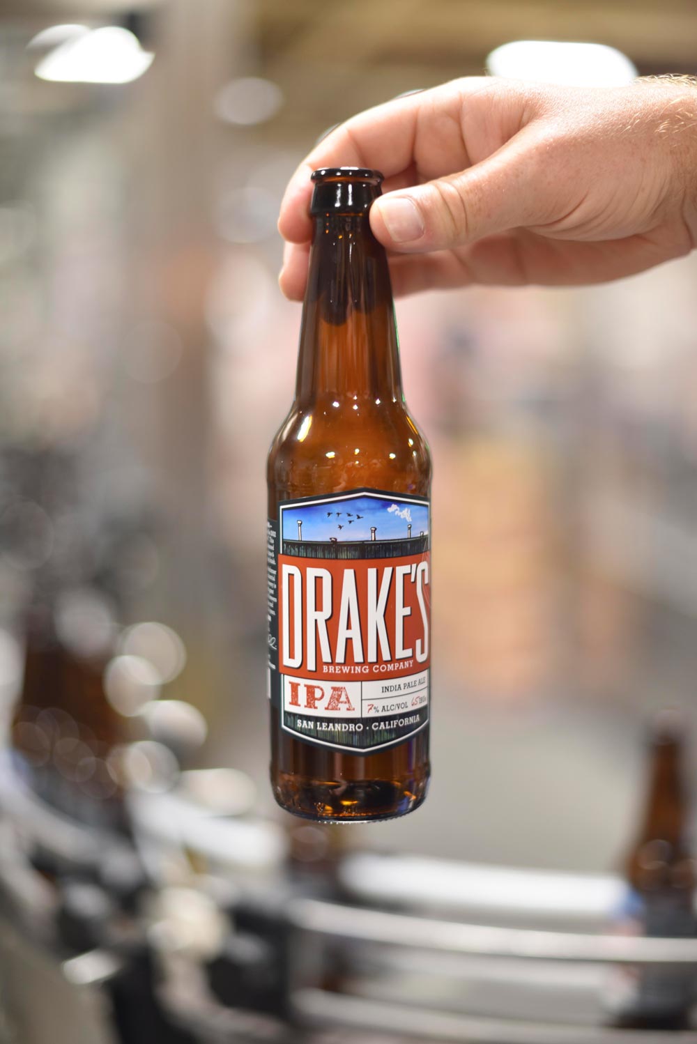 Head Brewer Christ Dunstan pulls a Drake's IPA bottle out of the line to inspect it  