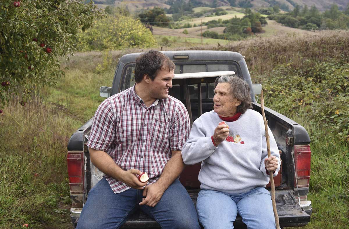 Jacob Gowan and his grandmother, Josephine (wearing an apple-embroidered sweatshirt) trade laughs, while snacking on apples