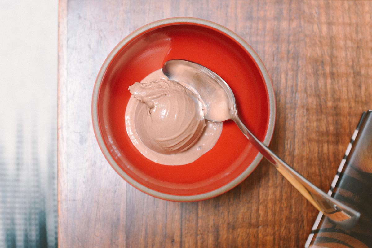 A scoop of Jone's chocolate gelato ice cream glistens in a red Heath Ceramics dish  