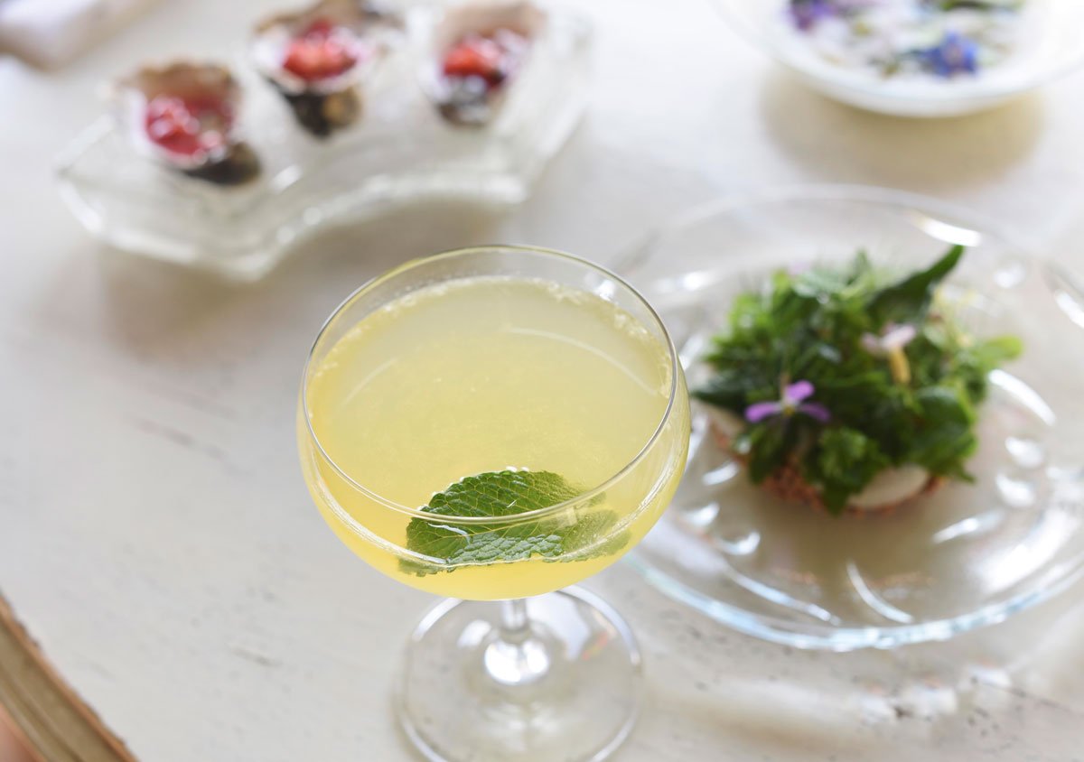 A mint leave floats in a fresh lemon cocktail.