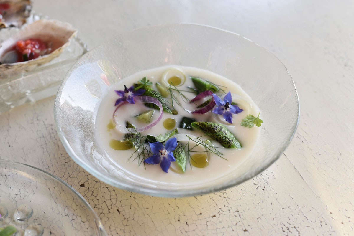 A light onion soup, served cold, is decorated with local fennel and edible flowers.