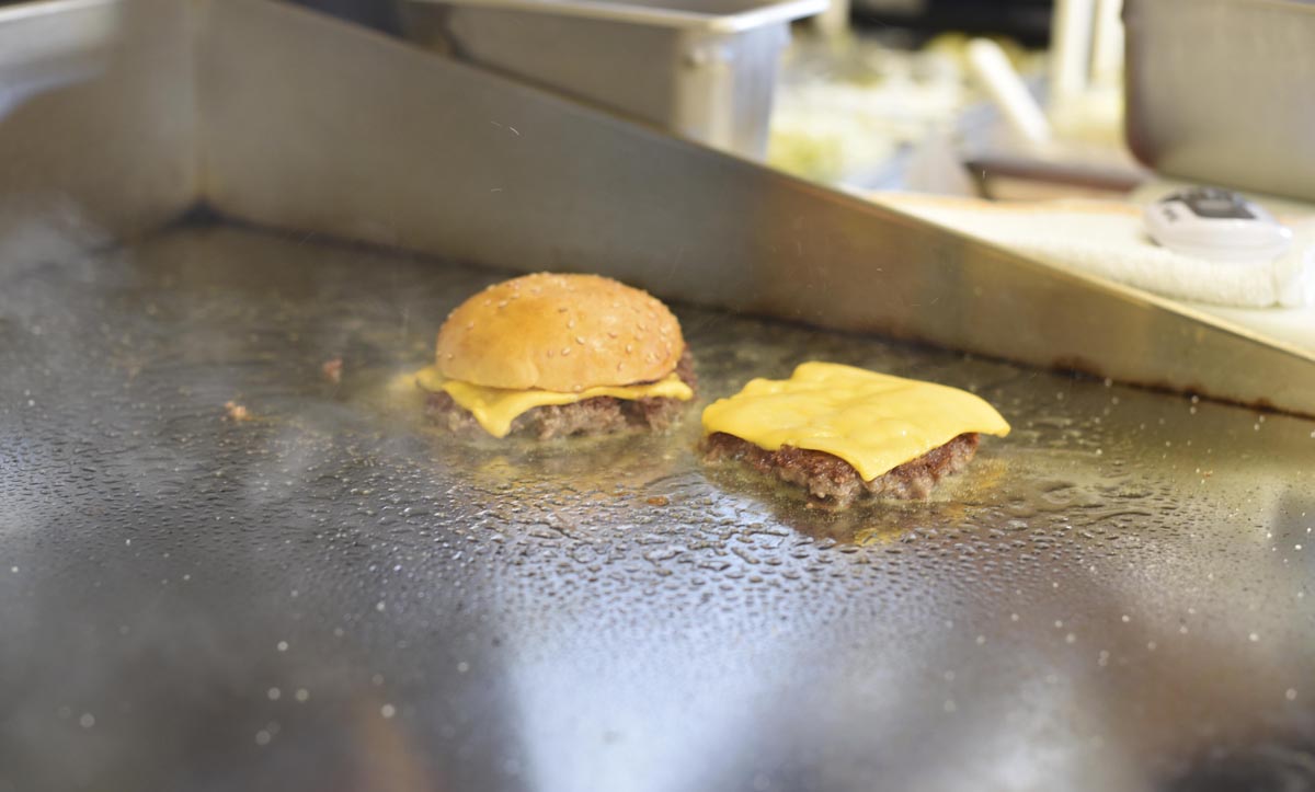A burger warms on the griddle  