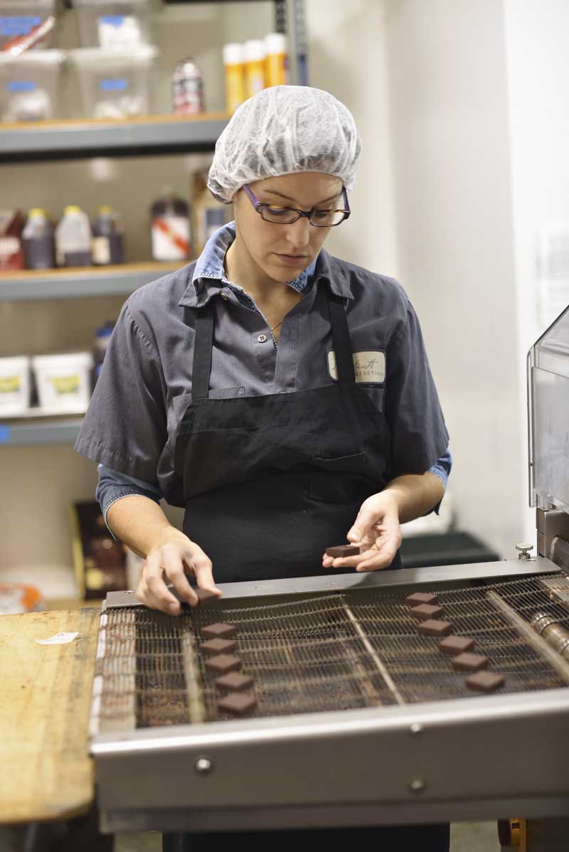 A chocolate worker places chocolates carefully  