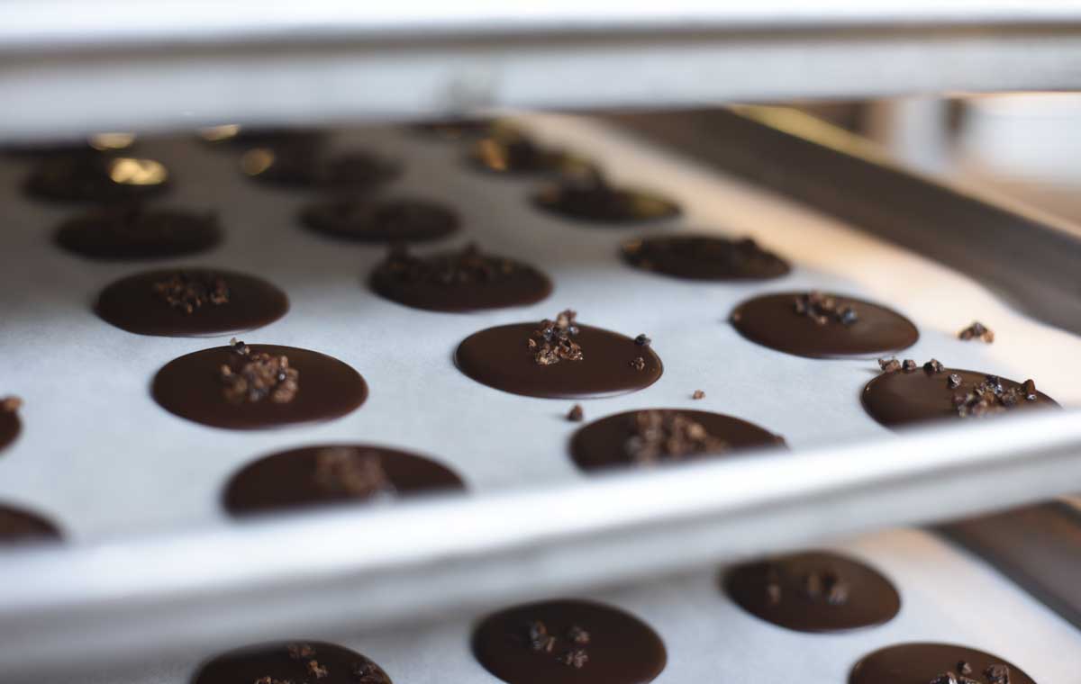 Thin chocolate crisps cool on wax paper before they're bagged  