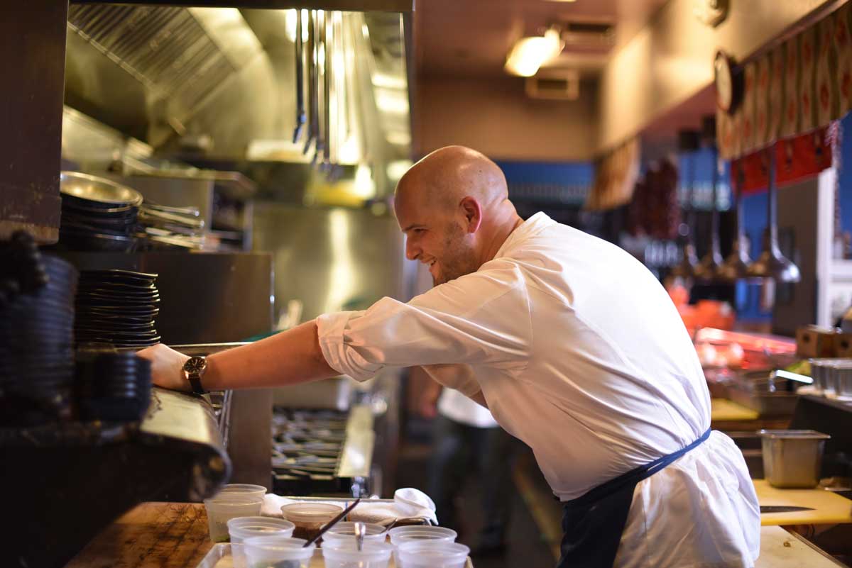 Chef August Schuchman slides a cast iron skillet into the hot oven 