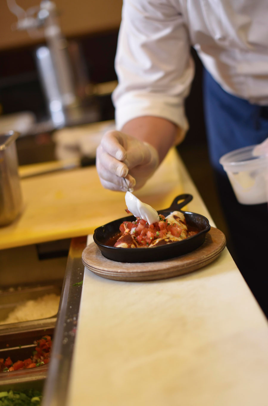 Chef August Schuchman adds a dolop of cream onto the enchilada dish 